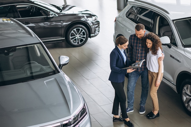 Young couple talking to a sales person in a car showroom