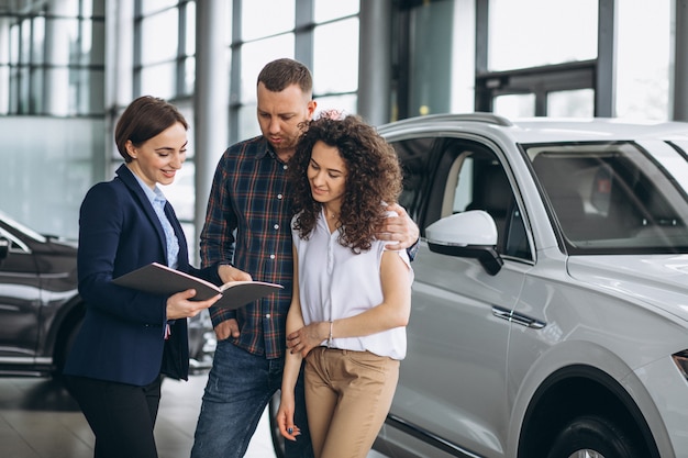 車のショールームで営業担当者に話している若いカップル