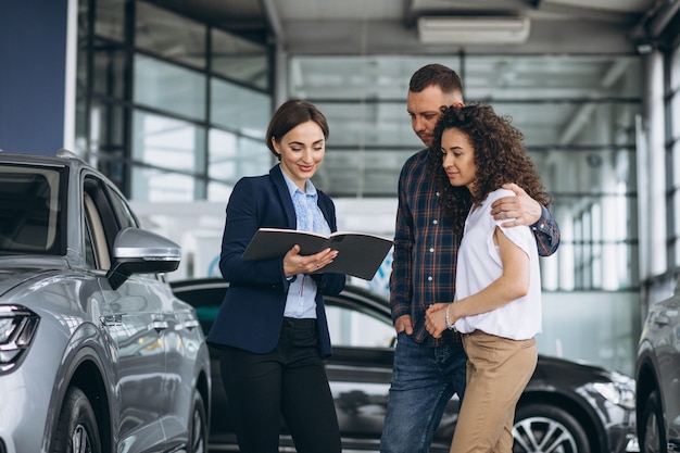 車のショールームで営業担当者に話している若いカップル