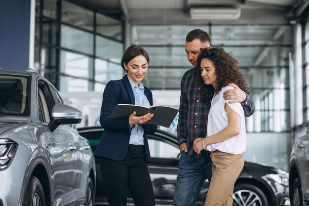 Young couple talking to a sales person in a car showroom