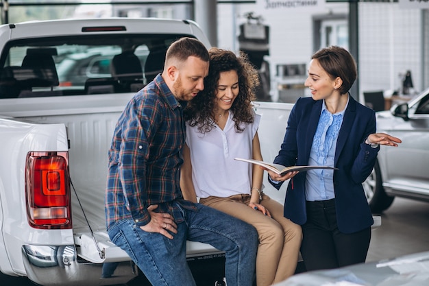 車のショールームで営業担当者に話している若いカップル