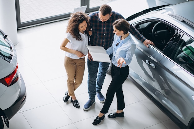 Young couple talking to a sales person in a car showroom