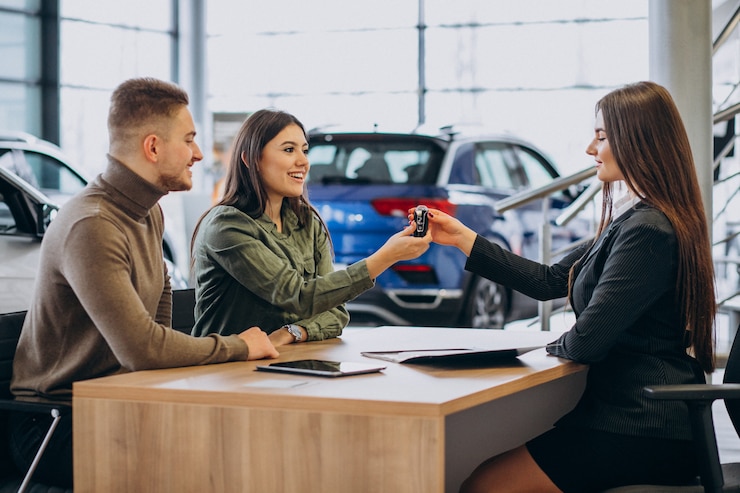 Free Photo young couple talking to a sales person in a car showroom