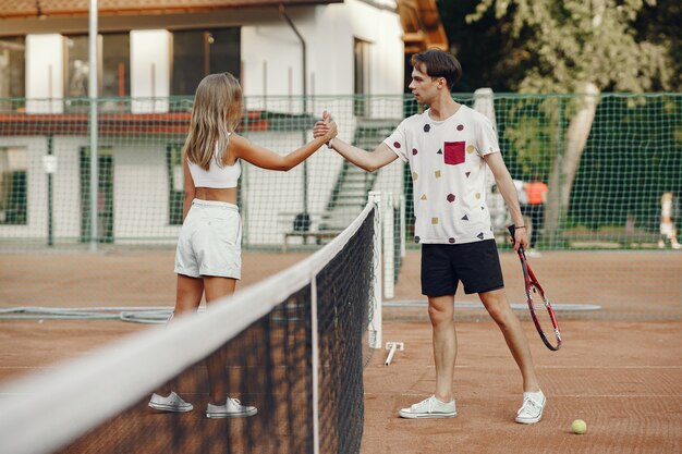 테니스 코트에 젊은 부부. 스포츠 옷에 두 테니스 선수.