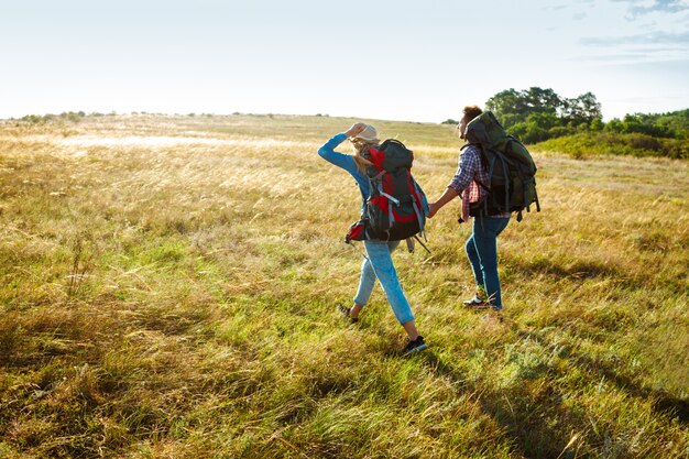 Young couple of travelers walking in field with pug dog