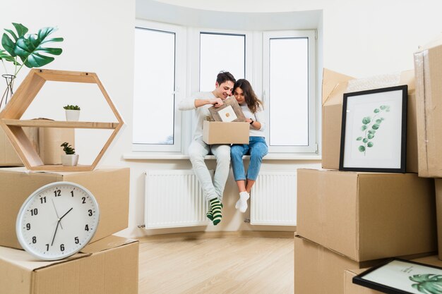 Young couple unpacking the cardboard boxes at their new house