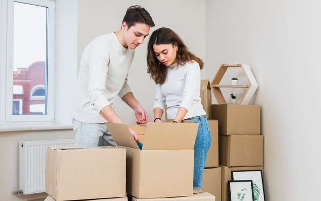 Young couple unpacking the cardboard boxes at their new house