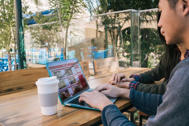 Giovani coppie che per mezzo del computer portatile alla caffetteria.