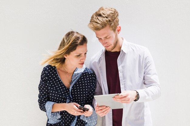 Молодая пара, используя смартфон и цифровой планшет