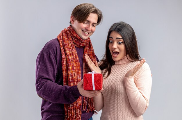 Young couple on valentines day smiling guy giving gift box to surprised girl isolated on white background