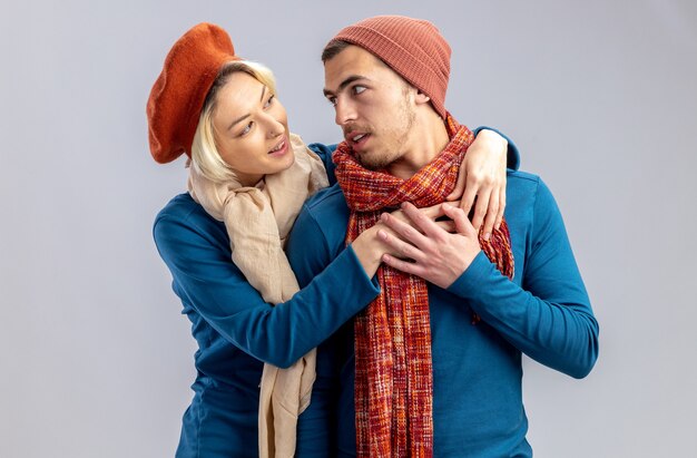 Young couple on valentines day wearing hat with scarf hugged and looking at each other isolated on white background