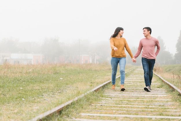 Free photo young couple walking along tracks