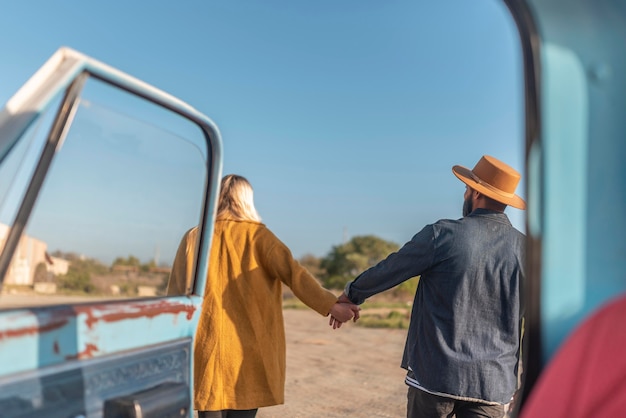 Young couple walking near the car and holding hands