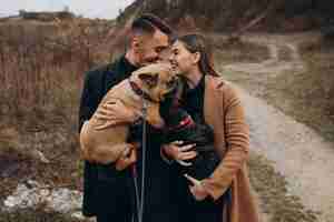 Free photo young couple walking their french bulldogs in park