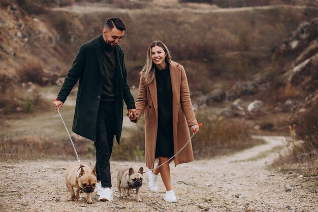 Young couple walking their french bulldogs in park