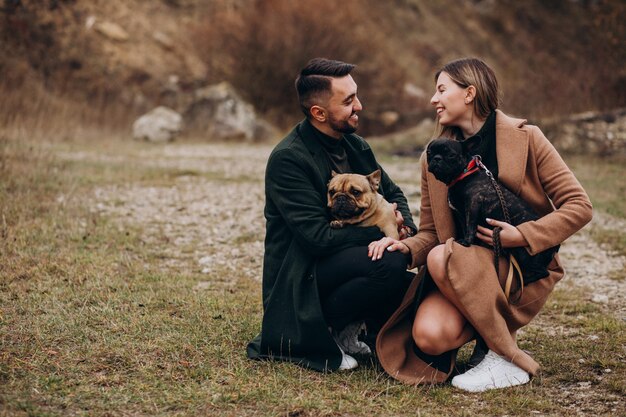 Young couple walking their french bulldogs in park