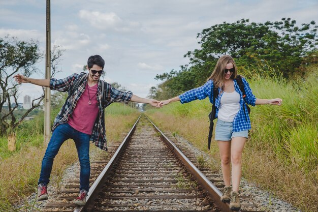 Young couple walking on train tracks holding hands