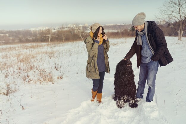 Young couple walking with a dog in a winter day