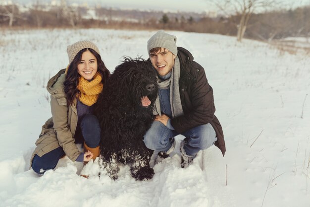 Young couple walking with a dog in a winter day