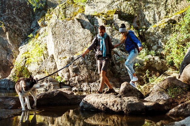 Молодая пара гуляет с собакой хаски в каньоне возле воды