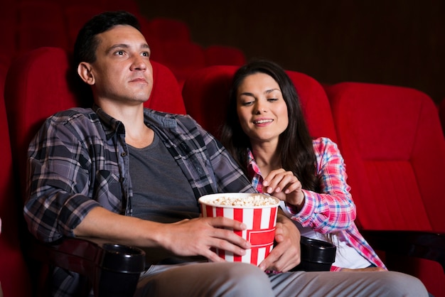 映画館で映画を見ている若いカップル