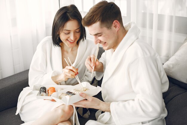 Young couple wearing bathrobes eating sushi.