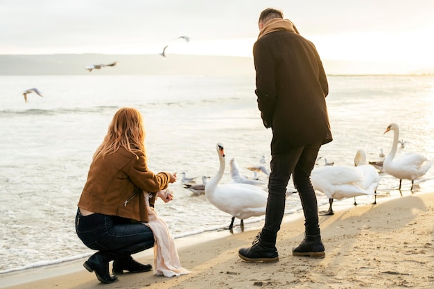 Giovane coppia in inverno sulla spiaggia con gli uccelli