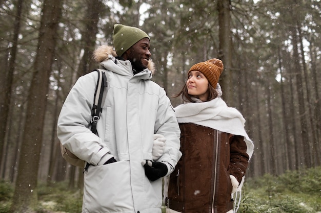 一緒に森の中を歩く冬の遠征の若いカップル