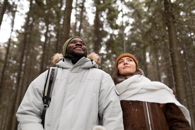 一緒に森の中を歩く冬の遠征の若いカップル