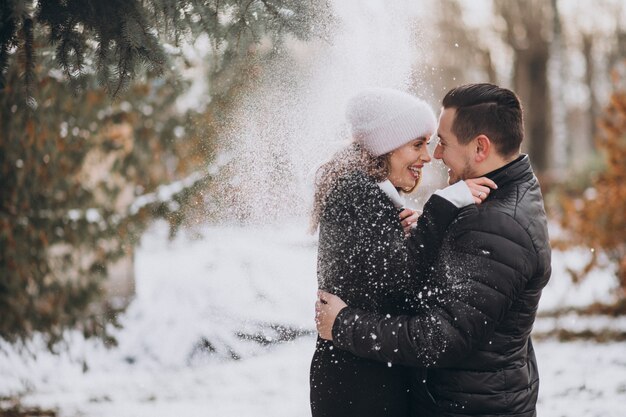 冬の木の下から雪の下で若いカップル