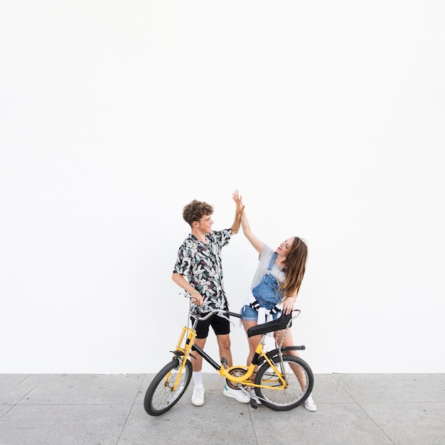 Бесплатное фото Молодая пара с велосипедом, давая высокий пять друг другу