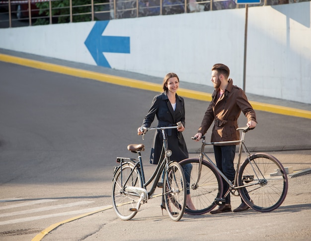 Free photo young couple with on a bicycle opposite city