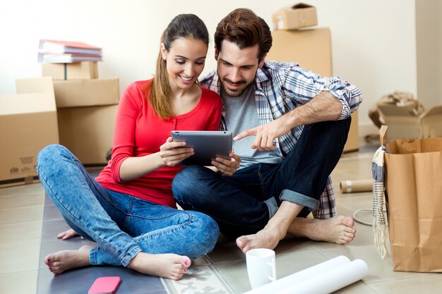 新しい家庭でデジタルタブレットを持つ若いカップル