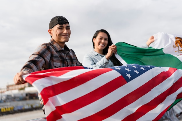 Free photo young couple with flags next to the river