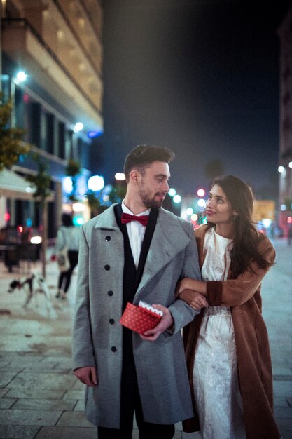 Young couple with gift boxes in street 