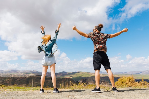 Young couple with hands up on hilltop