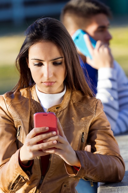 Young couple with smartphones in the park