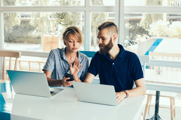 young couple working on laptops in a cafe doing a project, conferring, freelancers