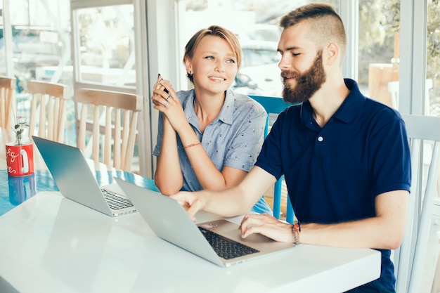 young couple working on laptops in a cafe doing a project, conferring, freelancers