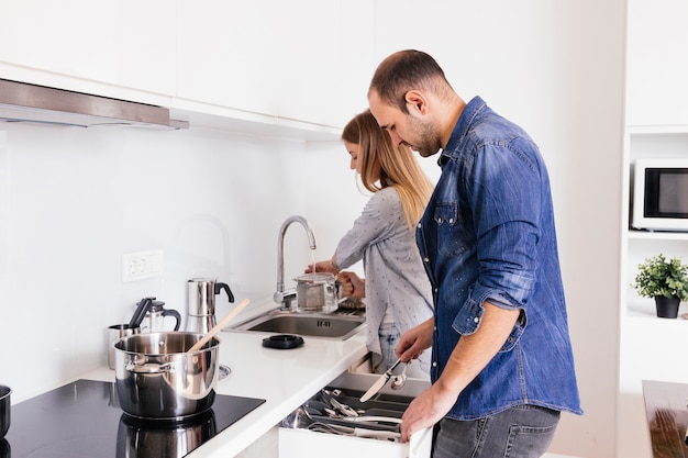 キッチンで調理器具を扱う若いカップル