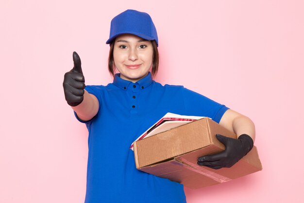 young courier in blue polo blue cap jeans holding package on pink