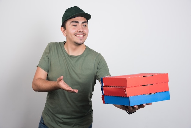 Free photo young courier carrying three boxes of pizza on white background. high quality photo