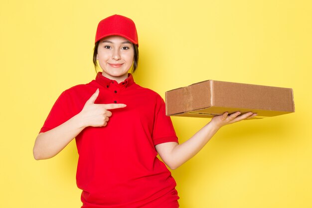 young courier in red polo red cap holding package smiling on yellow