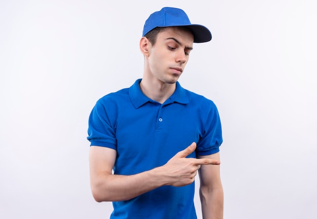 Young courier wearing blue uniform and blue cap angrily points on the left