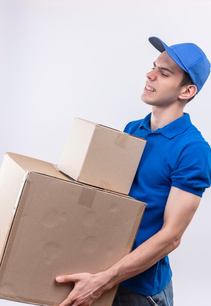 Young courier wearing blue uniform and blue cap can't hold boxes anymore