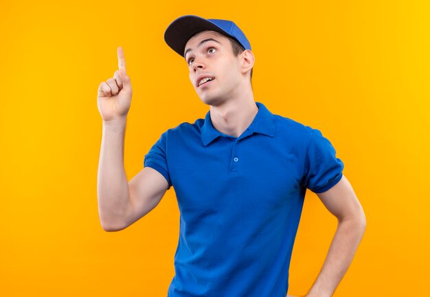 Young courier wearing blue uniform and blue cap doing forefinger up