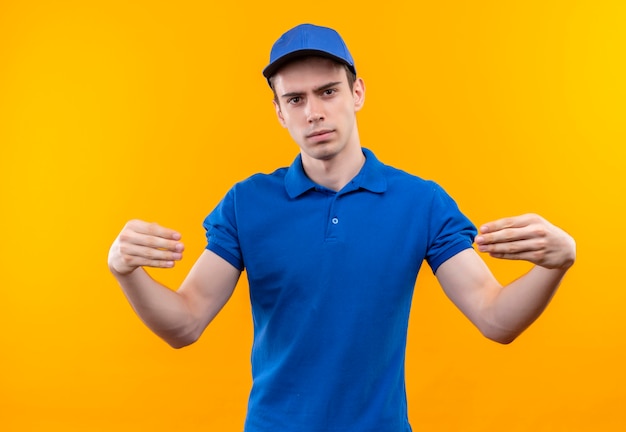 Young courier wearing blue uniform and blue cap seriously connects his fingers