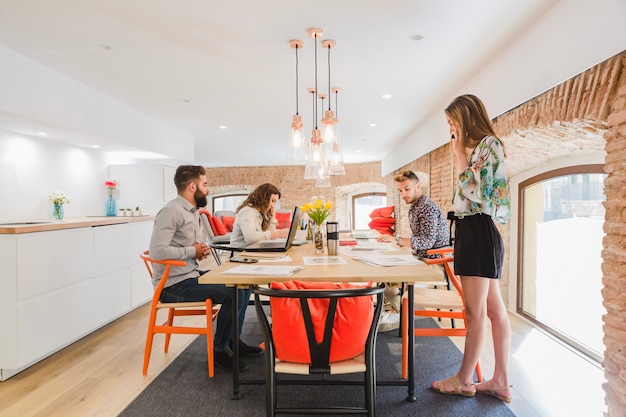 Free photo young coworkers gathering at table in office