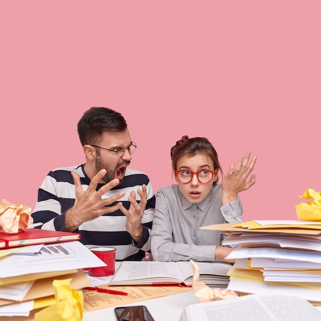 Young coworkers sitting at desk with documents