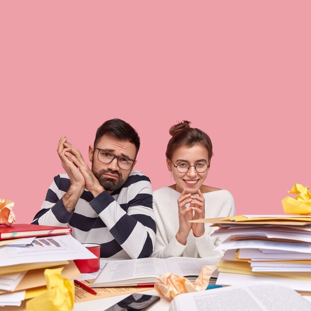 Young coworkers sitting at desk with documents